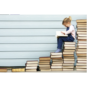 Small girl sitting on steps made out of piles of books.